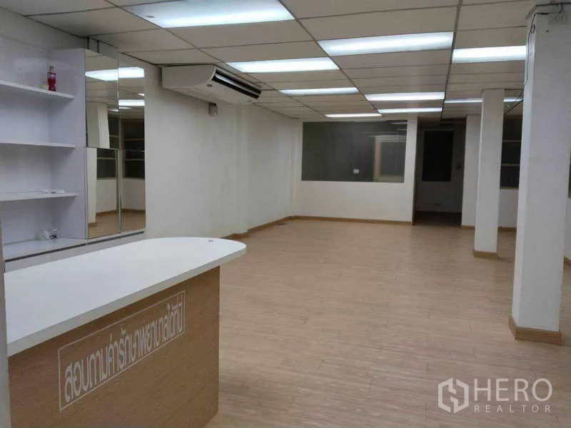 Office Space for rent in Bang Na, Bangkok - Reception counter with shelving facing a spacious office area under bright fluorescent lighting.