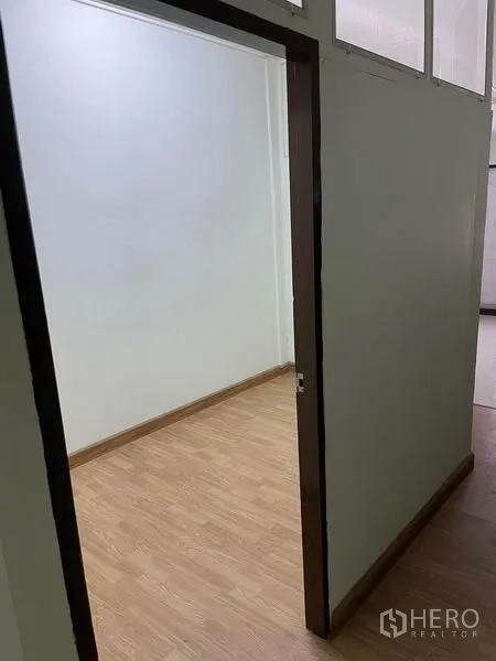 Shophouse for rent in Phaya Thai, Bangkok - Entry to a narrow office room with wood-look flooring and high windows.