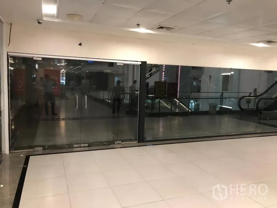 Retail Space for rent in Watthana, Bangkok - Vacant 177 sqm glass-front retail unit inside a Sukhumvit mall corridor with tiled floors and escalators nearby.