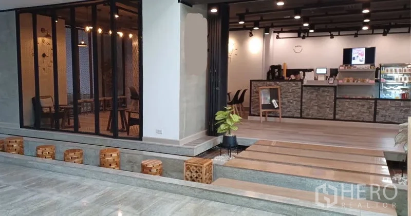 Retail Space for rent in Khlong Toei, Bangkok - Open-plan café-style retail unit with service counter, step walkway, indoor plants, and black track lighting.