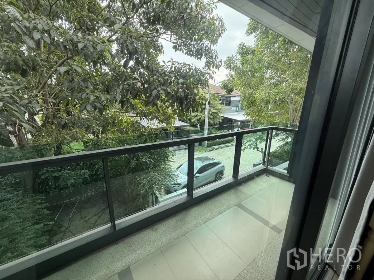 Detached House for rent in Bang Kapi, Bangkok - Upper-floor balcony with glass balustrade overlooking a tree-lined residential street.