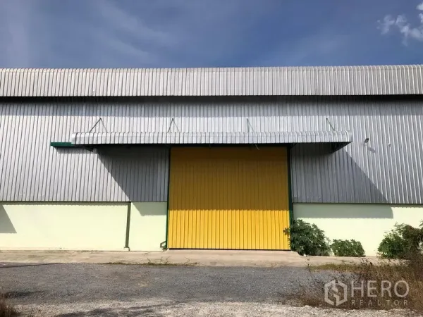 Warehouse for rent in Lat Krabang, Bangkok - Front elevation of the warehouse showing a wide yellow door and corrugated metal cladding.
