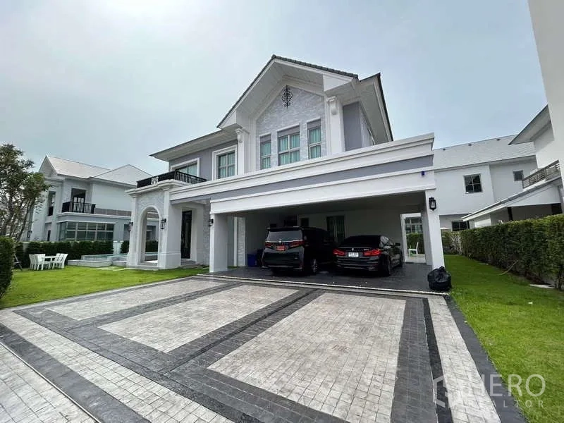 Detached House for rent or sale in Bang Phli, Samut Prakan - Two‑storey detached house with classic white facade, wide paved driveway and covered two‑car garage in Bang Phli.