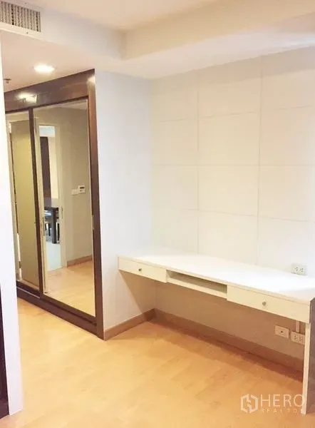 Condominium for rent in Khlong Toei, Bangkok - Corner workspace with built-in desk and mirrored wardrobe.