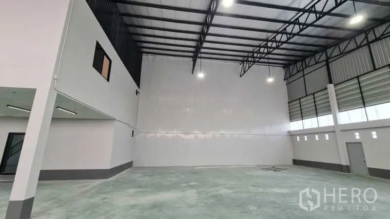 Warehouse for rent in Bang Bua Thong, Nonthaburi - High-clearance warehouse bay with insulated roof, white feature wall, and LED high-bay lights.