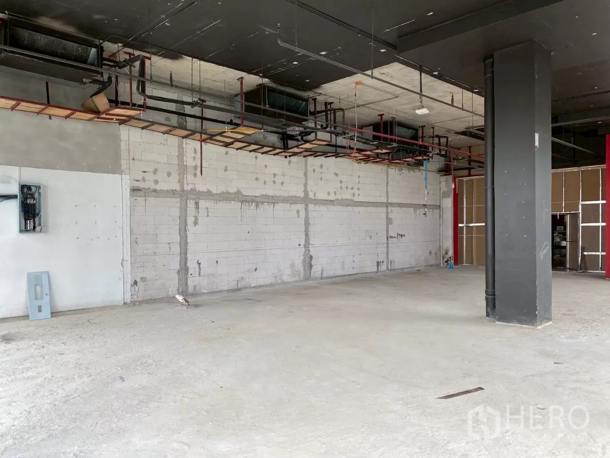 Retail Space for rent - Open-plan unit with exposed ceiling services, white block wall and concrete floor.