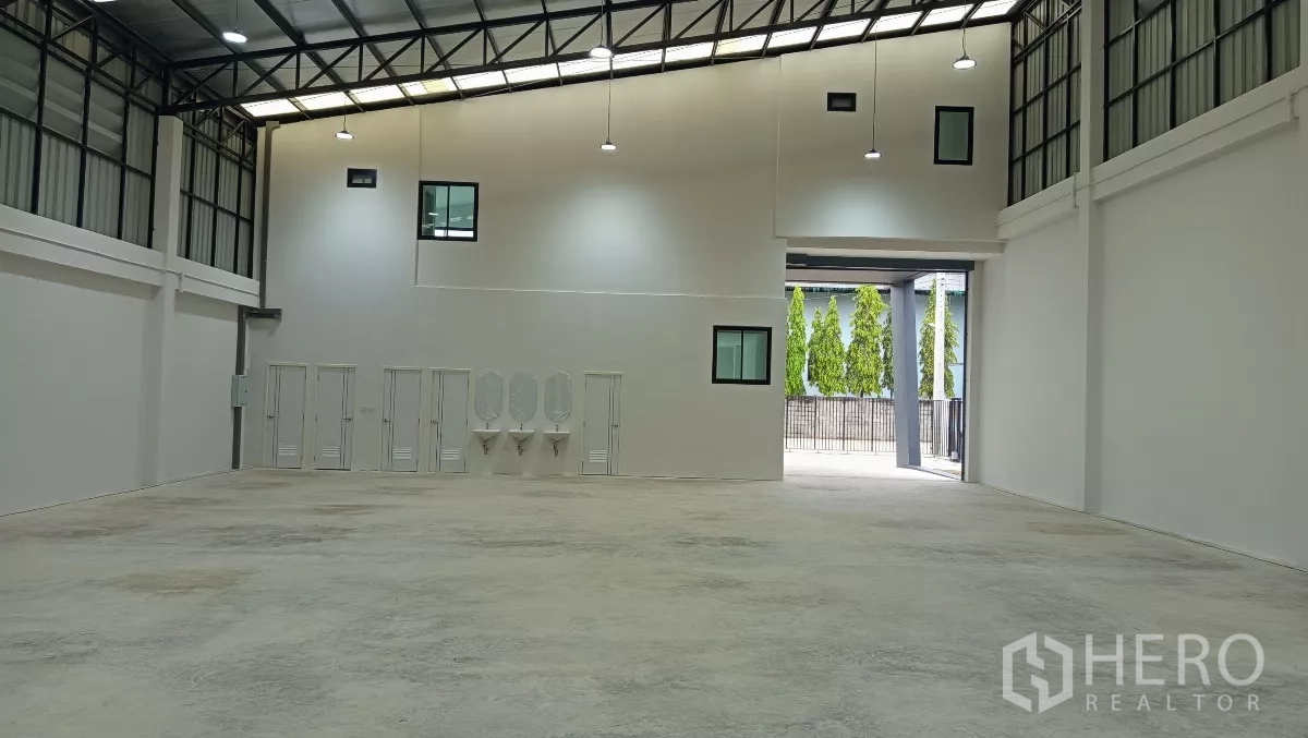 Warehouse for rent or sale in Lam Luk Ka, Pathum Thani - Interior of the warehouse facing the roller door with wash basins and multiple restrooms.