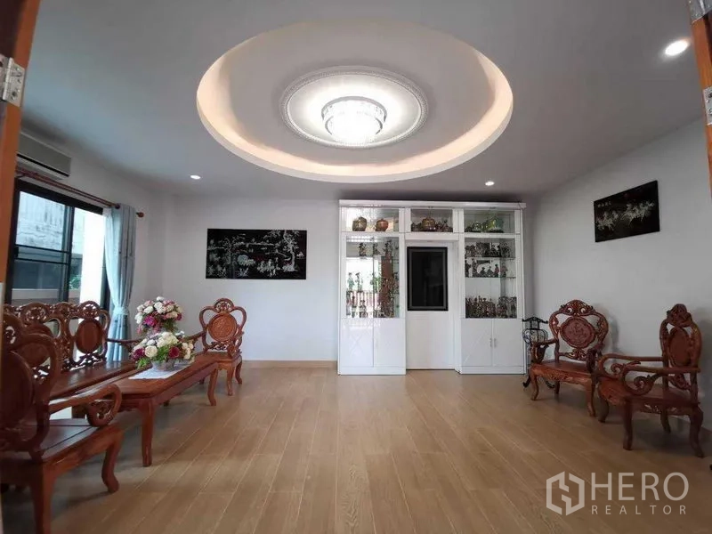 Detached House for rent in Prawet, Bangkok - Formal sitting room with carved wooden furniture, cove ceiling chandelier and white display cabinetry.