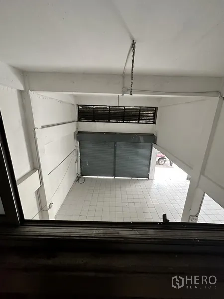 Shophouse for rent or sale in Watthana, Bangkok - View from mezzanine toward front roller shutters and double-height space.