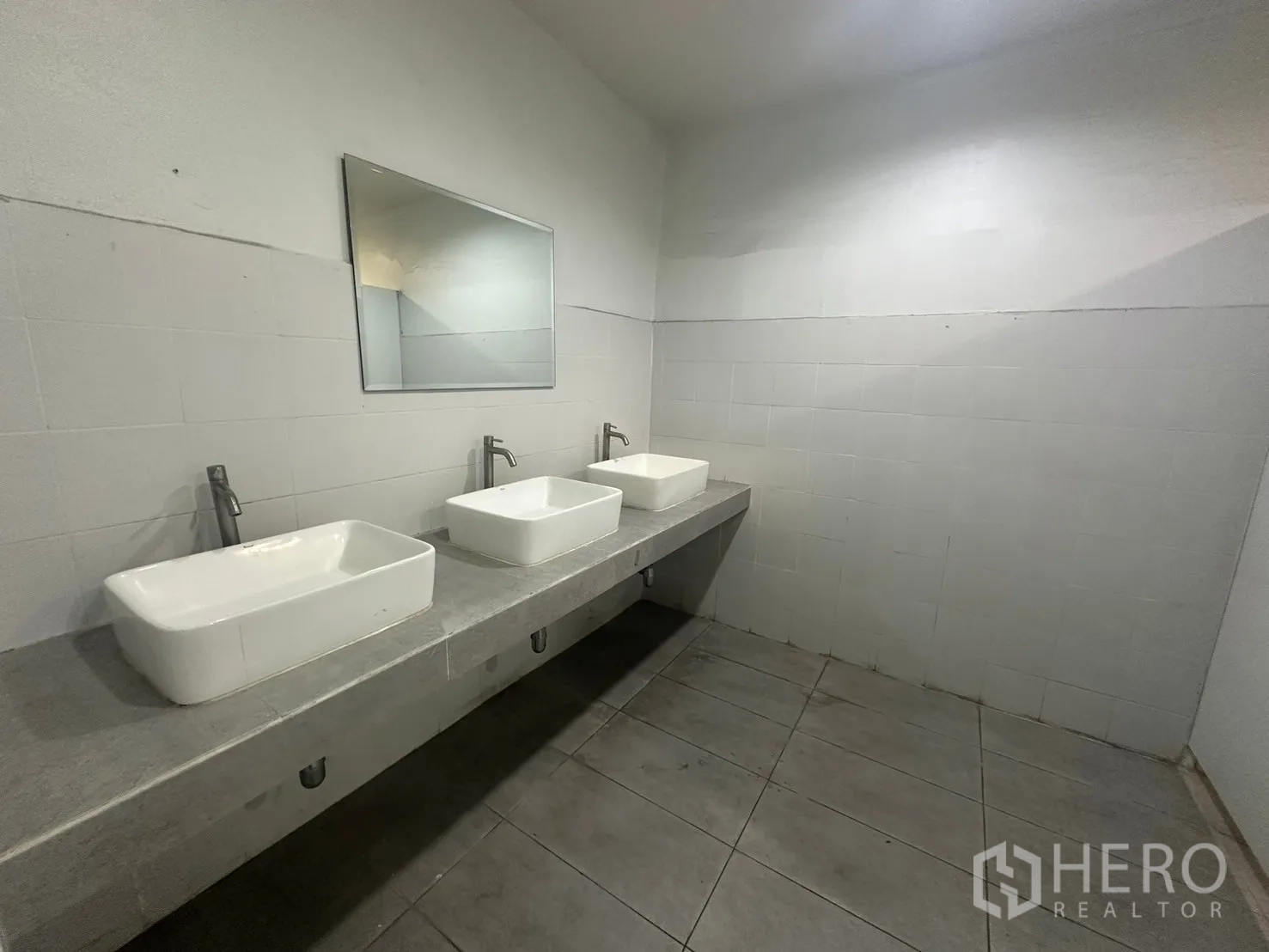 Warehouse for rent in Din Daeng, Bangkok - Restroom wash area with three rectangular vessel sinks and a wall mirror.