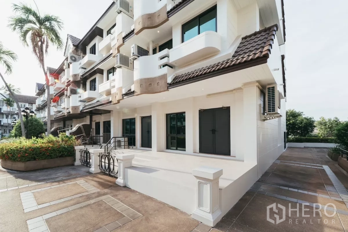 Townhouse for rent in Watthana, Bangkok - Side view of white townhouse row with landscaped walkway and balconies near Phra Khanong.