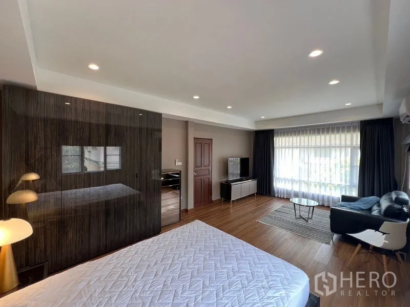 Detached House for sale in Mueang Pathum Thani, Pathum Thani - Spacious master suite with seating area, TV console and wide windows with sheer curtains.