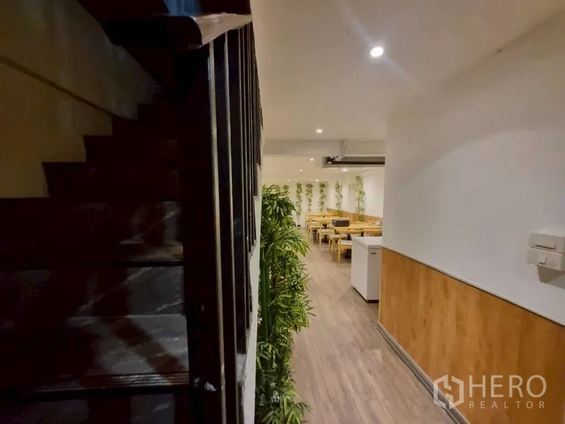 店屋 出租或出售在Watthana, Bangkok - 楼梯通往用餐楼层，沿墙有绿植。