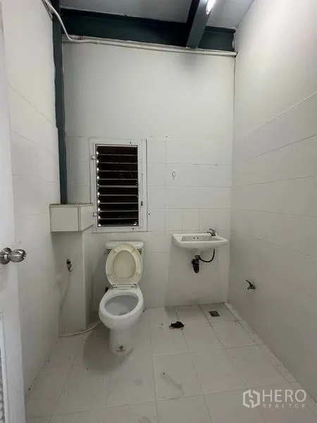 Factory for rent in Bang Bua Thong, Nonthaburi - Simple restroom with toilet, sink and tiled walls inside the factory building.