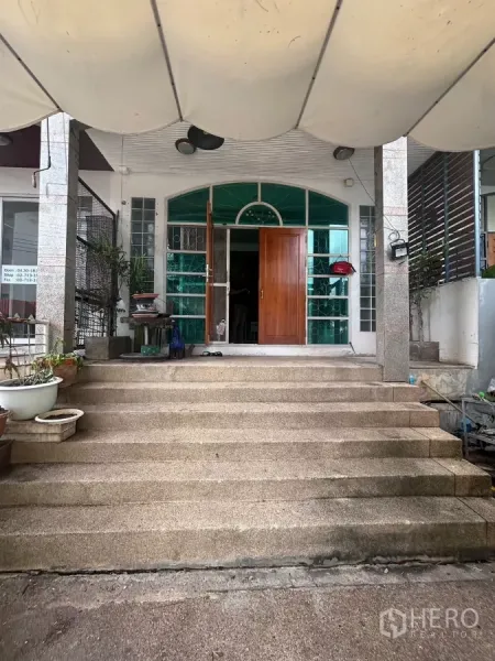 店屋 出租在Watthana, Bangkok - 正面宽阔台阶通向拱形玻璃入口，配实木大门。