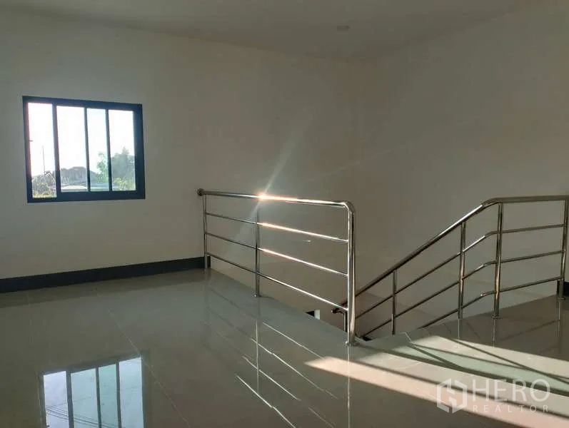 Factory for rent or sale in Sai Noi, Nonthaburi - Bright upper landing with window and stainless balustrade over glossy tiled flooring.