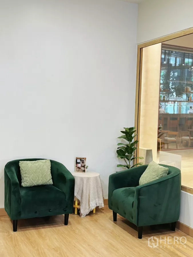 Retail Space for rent - Cozy waiting area with two green velvet armchairs, side table and indoor plant beside a glass partition.