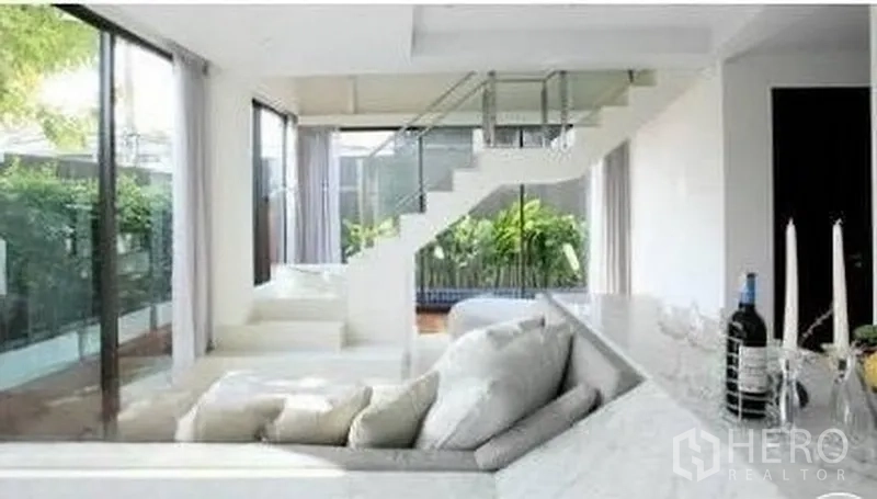 Townhouse for rent in Watthana, Bangkok - Bright living area with glass staircase and garden views through sliding doors.