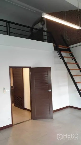 Townhouse for rent or sale in Khlong Toei, Bangkok - Loft-style mezzanine with ladder above a high-ceiling room.