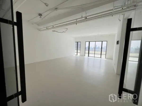 Office Space for rent in Watthana, Bangkok - Bright open-plan office with white walls and full-height windows showcasing Bangkok skyline views.