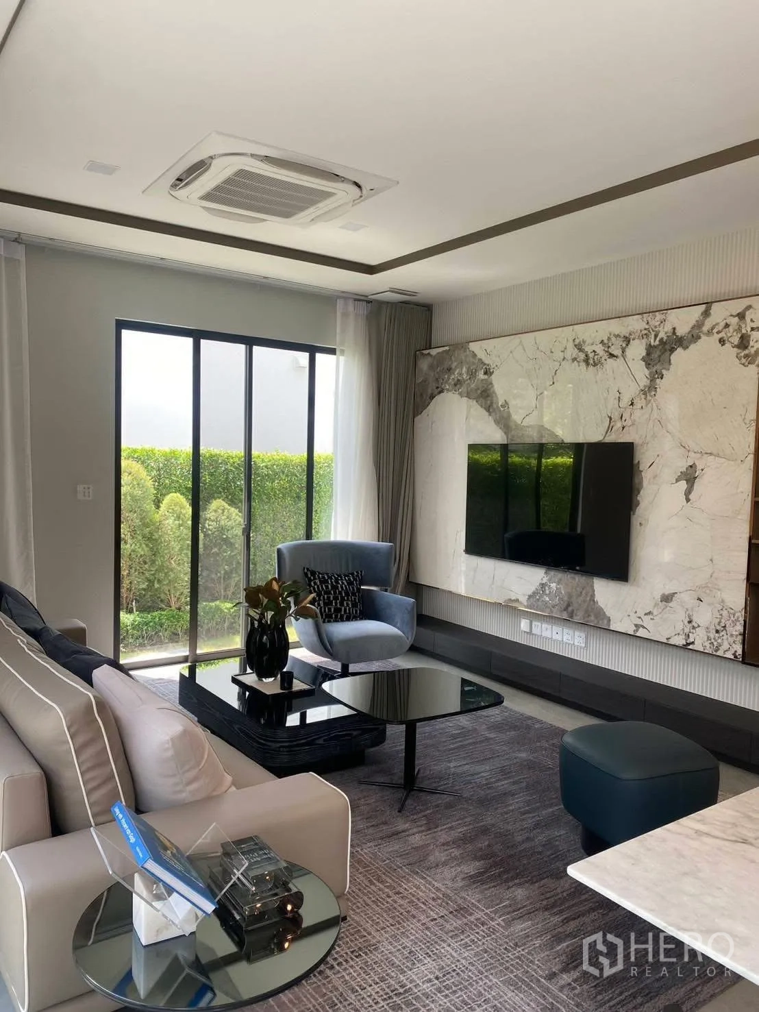 บ้านเดี่ยว for rent or sale in Bang Phli, Samut Prakan - ห้องนั่งเล่นสว่างด้วยผนังลายหินอ่อน ทีวี และวิวสวน.