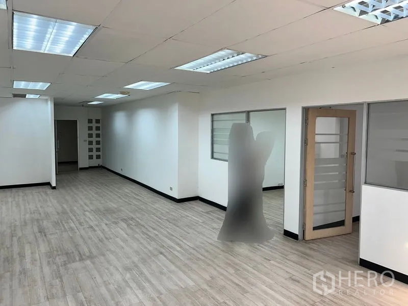 Office Space for rent in Pathum Wan, Bangkok - Spacious office floor with glass-partitioned rooms, wood-look floors and fluorescent lighting.