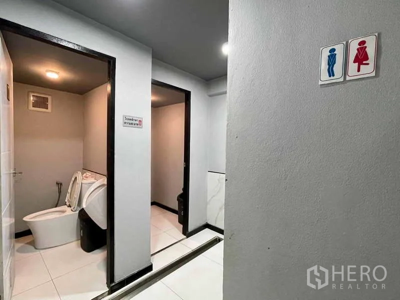 Shophouse for rent in Lat Phrao, Bangkok - Separate male and female public restrooms finished in neutral tiles.