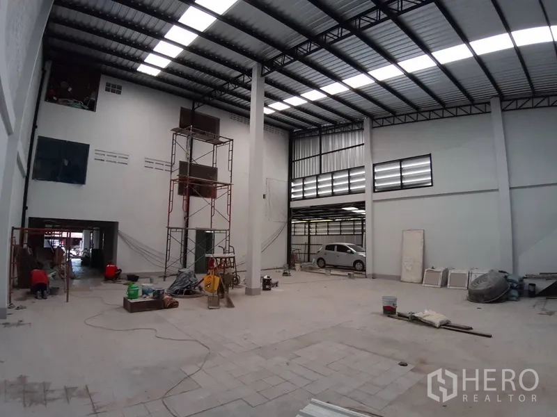 Warehouse for rent in Chatuchak, Bangkok - Open‑plan warehouse with central column, roller door loading bay and a parked vehicle.