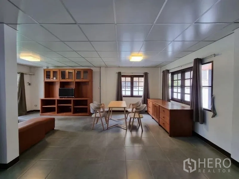 Detached House for rent in Nonthaburi - Spacious living and dining area with large windows, tiled floors, and a built-in cabinet.