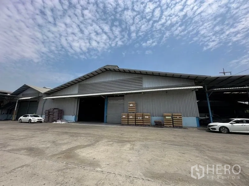 Warehouse for rent in Bang Pa-in, Phra Nakhon Si Ayutthaya - Angled exterior of the warehouse showing loading area, parked cars and blue sky.
