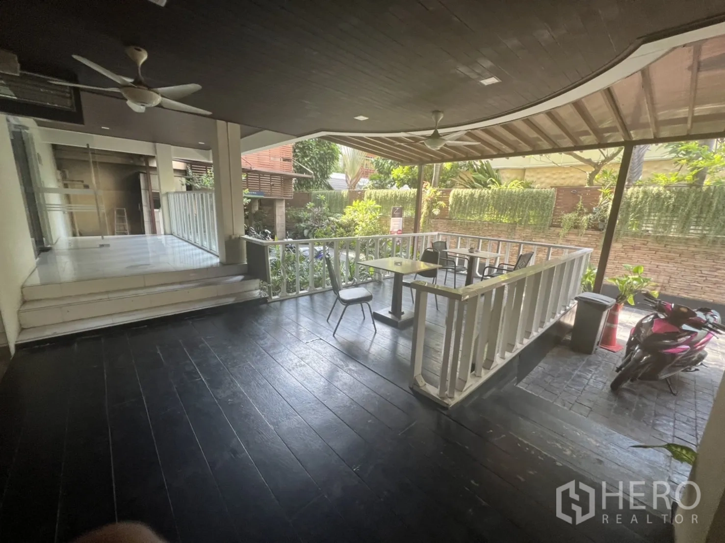 Retail Space for rent in Khlong Toei, Bangkok - Covered veranda with ceiling fans, railings, small tables and greenery along the driveway.