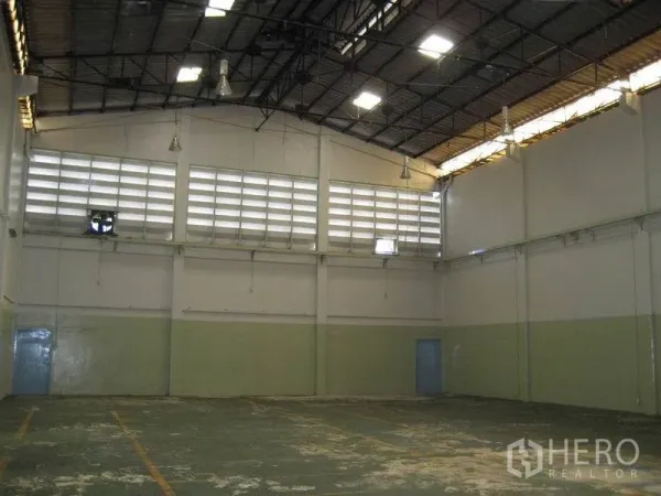 工厂 出租在Bang Sao Thong, Samut Prakan - 宽阔仓库空间，屋顶天窗、吊灯与地面标线。