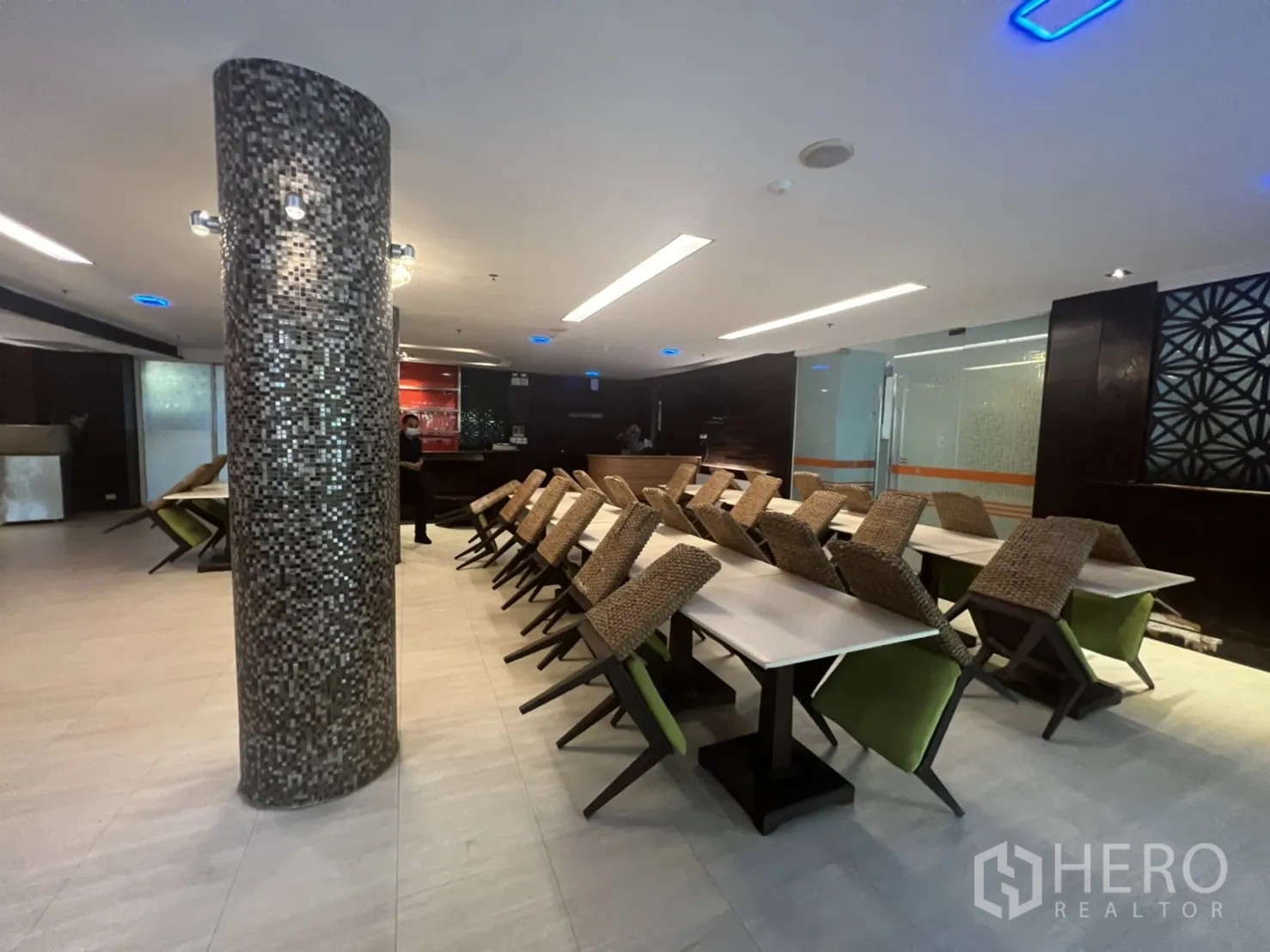 Retail Space for rent in Khlong Toei, Bangkok - Empty dining room with chairs stacked on tables, mosaic pillar and bright ceiling lights.
