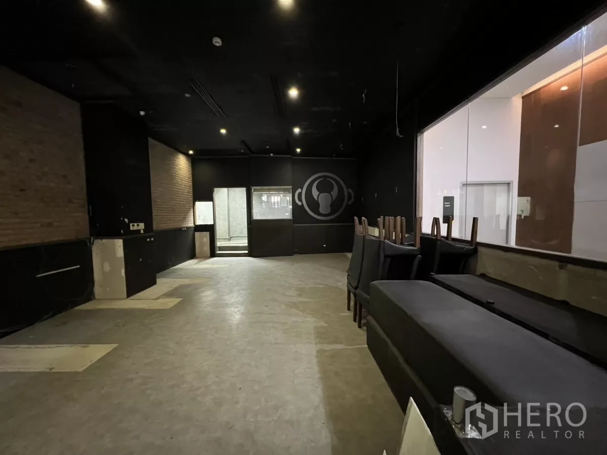 Retail Space for rent - Wide dining hall with black ceiling, brick accent wall and internal window to the kitchen.