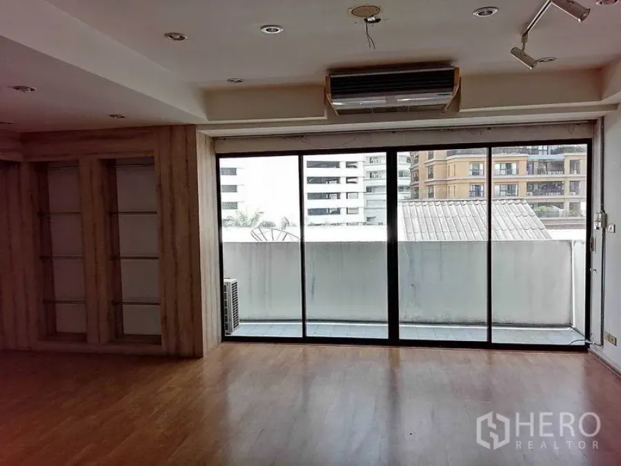 Office Space for rent in Khlong Toei, Bangkok - Spacious office with wood flooring, recessed lights and sliding glass doors opening to a balcony with city views.