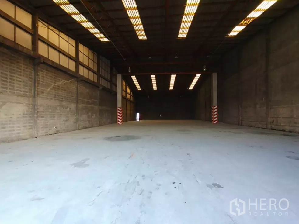 Factory for rent in Phra Pradaeng, Samut Prakan - Spacious factory interior with high ceiling, strip lighting and heavy‑duty concrete floor ideal for forklifts.