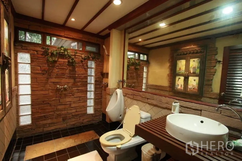 Detached House for rent in Bang Phli, Samut Prakan - Spa-style bathroom with stone accent walls, glass-block windows, a large mirror and a vessel sink.