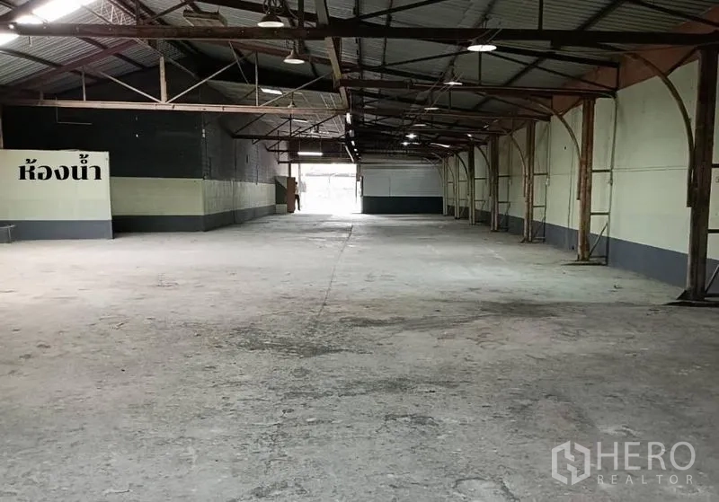 Warehouse for rent in Bang Khen, Bangkok - Long storage hall with high ceiling, exposed beams and durable concrete flooring.