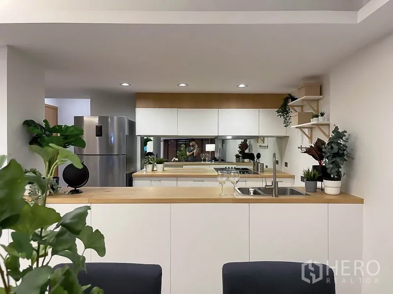 Townhouse for rent in Khlong Toei, Bangkok - Contemporary kitchen with white cabinetry, wood countertops, and stainless fridge.