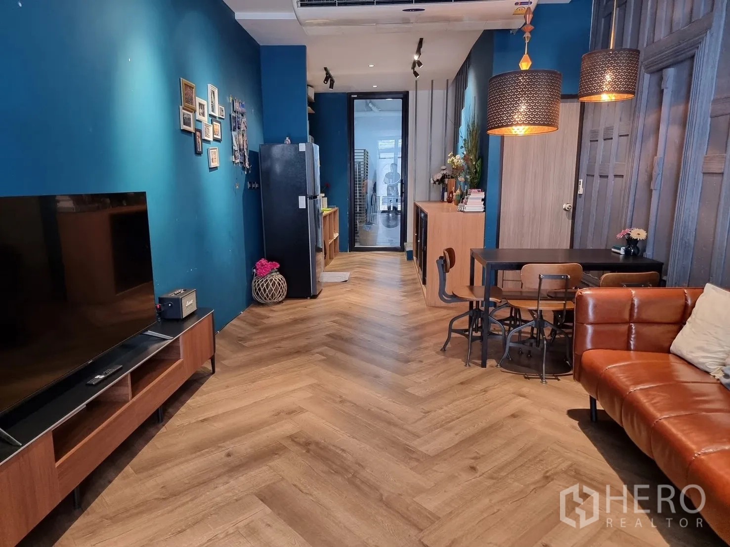 联排别墅 for rent in Watthana, Bangkok - 客厅配电视柜，鱼骨拼木地板，吊灯、餐桌与冰箱。
