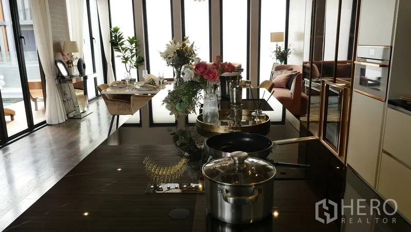 Detached House for sale in Prawet, Bangkok - Close view of glossy kitchen island with built‑in hob, cookware and floral decor.