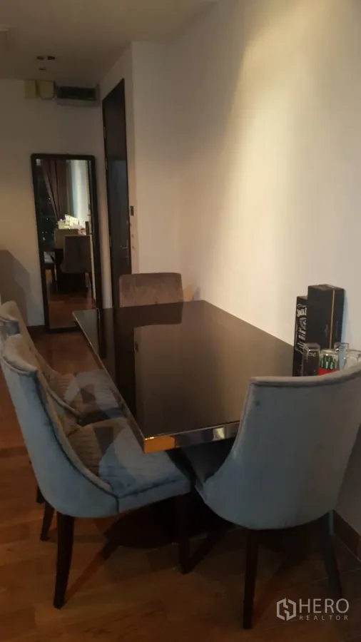 Condominium for rent in Pathum Wan, Bangkok - Cozy dining corner with a black glass table, four upholstered chairs and warm wood flooring in a modern Bangkok condo.