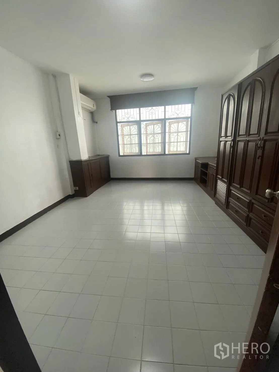 Townhouse for rent in Huai Khwang, Bangkok - Bedroom with air conditioning, decorative window grills, and built-in wooden wardrobes.