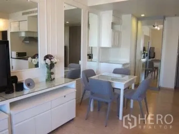 Condominium for rent in Khlong Toei, Bangkok - Dining corner with four-seat table, mirrored wall and built-in storage.