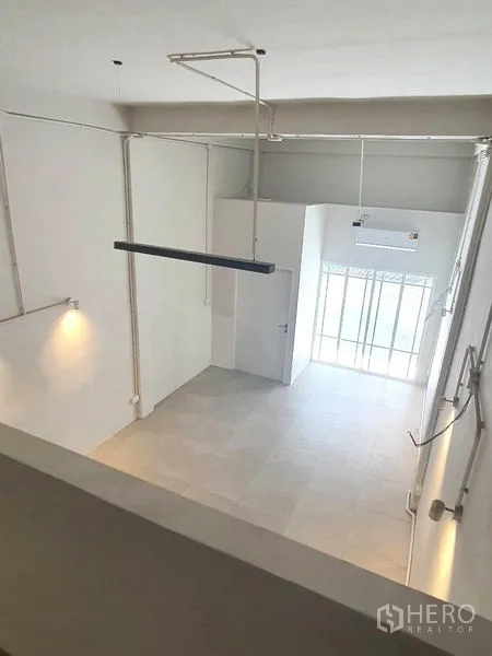Shophouse for rent in Phra Khanong, Bangkok - View from the mezzanine overlooking the tall retail space and street-facing glass entrance.