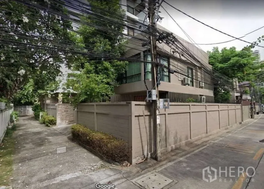 Detached House for rent - Exterior angle of the walled detached house along a narrow residential street with greenery.