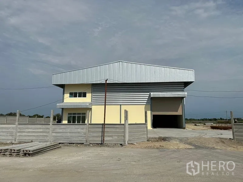 Warehouse for rent or sale in Bang Phli, Samut Prakan - New warehouse exterior with metal cladding, yellow walls, a high roller shutter and wide driveway in an open Bang Phli industrial area.