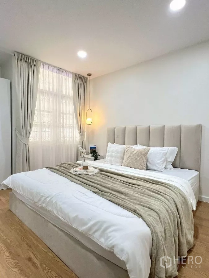 Detached House for rent in Huai Khwang, Bangkok - Primary bedroom wide shot with upholstered headboard, pendant lighting and layered bedding.