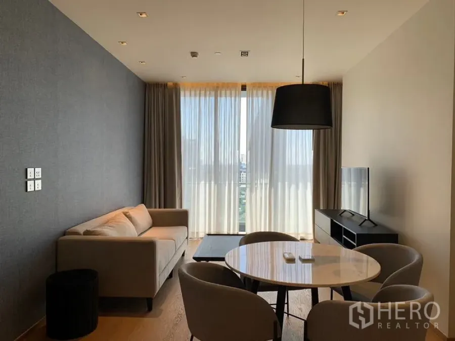 Condominium for rent in Khlong Toei, Bangkok - Wide view of living-dining zone with TV console and full-height windows letting in natural light.