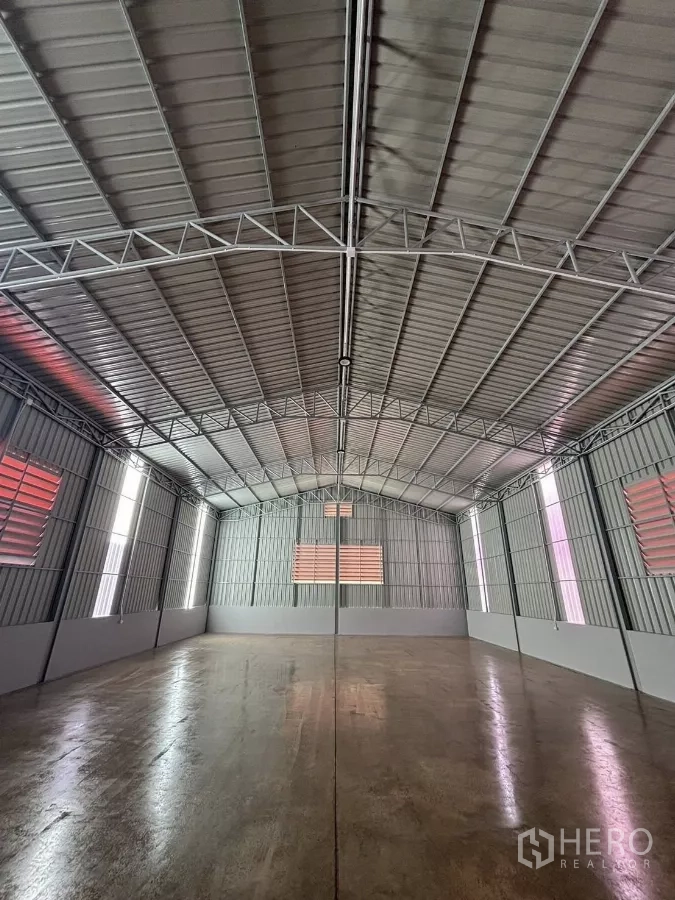 Warehouse for rent in Nonthaburi - Spacious warehouse interior with high steel roof, ventilation louvers and polished concrete floor.